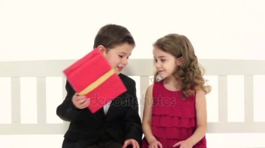 Küçük çocuk bir çift pantolon ve kız geri onu yanağından öper verir alır. Beyaz arka plan. Ağır çekim. Yakın çekim