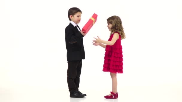 Little boy gives his girlfriend a gift, she kisses him gently on the cheek. White background. Slow motion — Stock Video