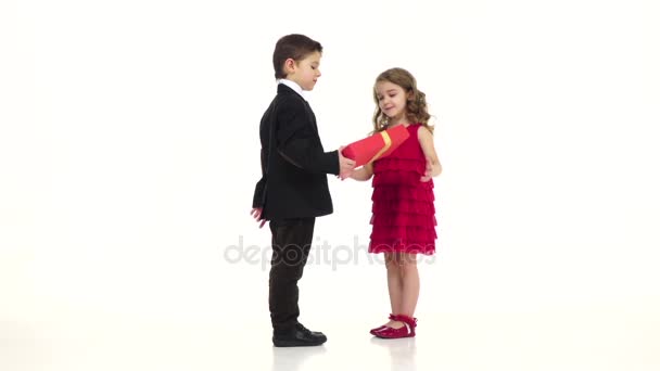 Little boy gives his girlfriend a gift, she kisses him gently on the cheek. White background. Slow motion — Stock Video