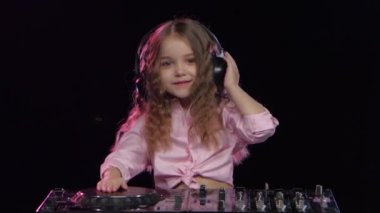 Küçük kız kulaklık dj konsolu için çalış. Siyah arka plan
