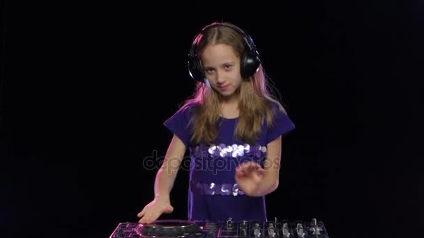 Teen girl dj in headphones plays for console. Black background — Stock Video