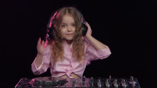 Little girl dj in headphones playing on vinyl. Black background — Stock Video