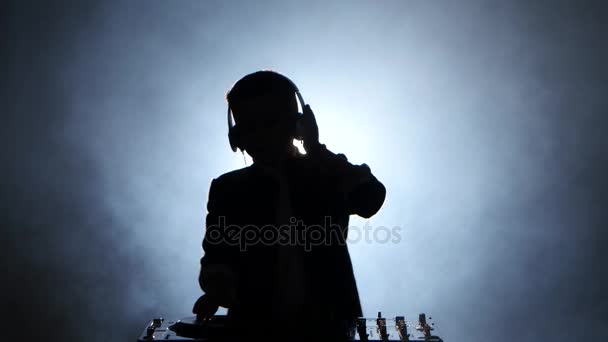 Silhouette boy dj in cuffia che suona su vinile. Fondo fumoso — Video Stock