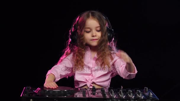 Fille dans les écouteurs joue sur la plaque tournante. Fond noir, ralenti — Video