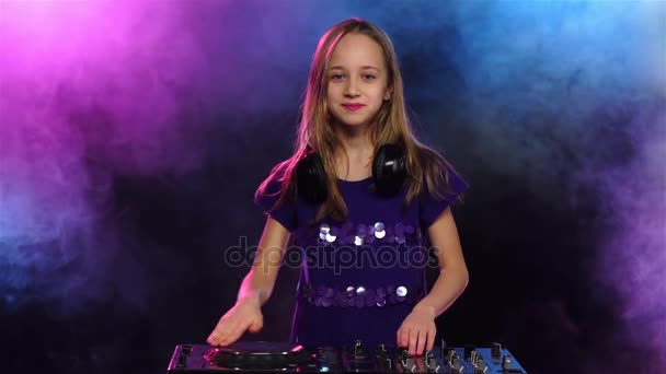 Girl dj in headphones plays on smoky background, slow motion — Stock Video