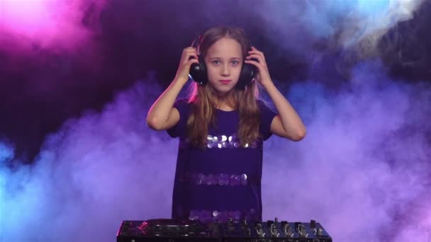 Flickan bär hörlurar och startar spelar på skivspelare. Slow motion — Stockvideo