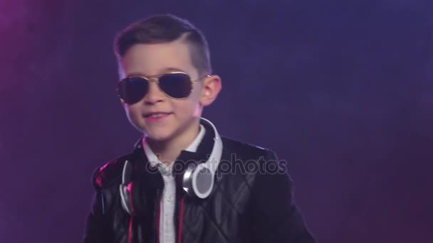 Boy in stylish glasses dances on colored smoky, slow motion — Stock Video