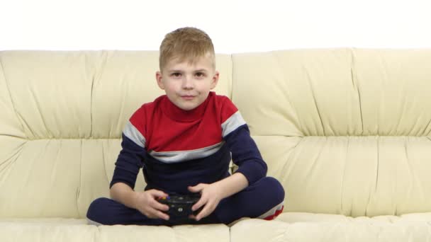 Menino com consola de jogos jogando videogame no sofá — Vídeo de Stock