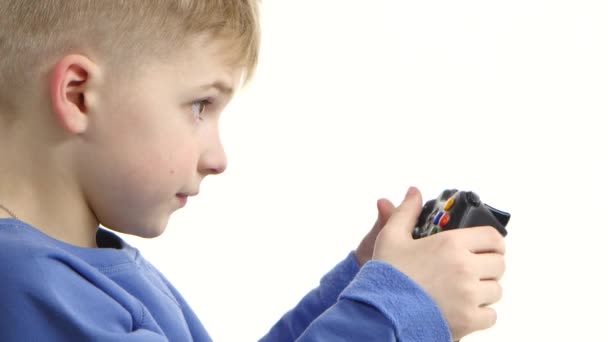 Мальчик играет в видеоигру с игровой приставкой. Белый фон, крупный план — стоковое видео