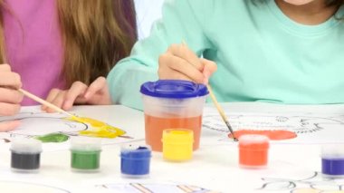 Fırçalar ve boya yardımı ile küçük çocuk süslemeleri çizimler, onlar gibi. Yakın çekim. Beyaz arka plan