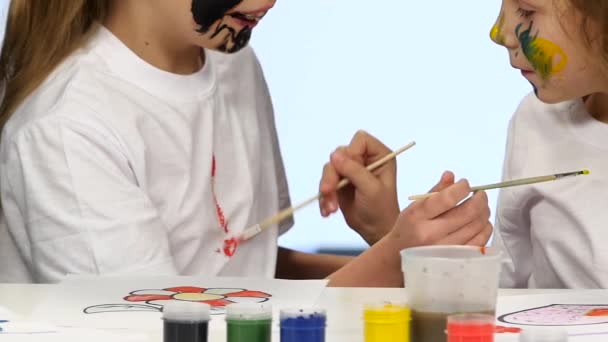 Los niños pintan con pintura en la ropa. Fondo blanco. Movimiento lento — Vídeos de Stock