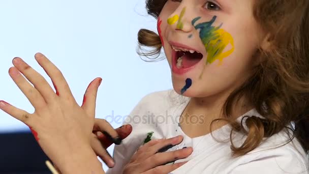 La niña dibuja sus palmas en la camisa. Fondo blanco. Movimiento lento — Vídeos de Stock