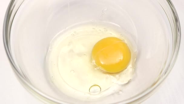 Breaking eggs for cooking in glass plate, slow motion. Closeup — Stock Video