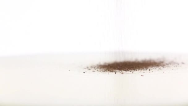 Zwarte gemalen peper toegevoegd aan de melk. Super close-up, slow-motion — Stockvideo