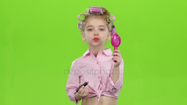 Dziecko w lokówki w dłoniach trzyma lustro i farby szminki pomadki. Zielony ekran. Zwolnionym tempie — Wideo stockowe