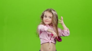 Çocuk curlers kaldırır ve onun uzun saç tarama başlar. Yeşil ekran. Ağır çekim