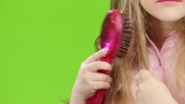 Dítě drží hřeben a česání její dlouhé a hedvábné vlasy. Zelená obrazovka. Zpomalený pohyb — Stock video