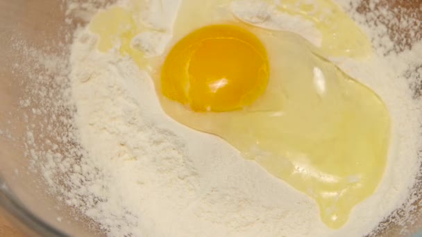 Куриное яйцо падает в пшеничную муку в замедленной съемке, крупным планом — стоковое видео