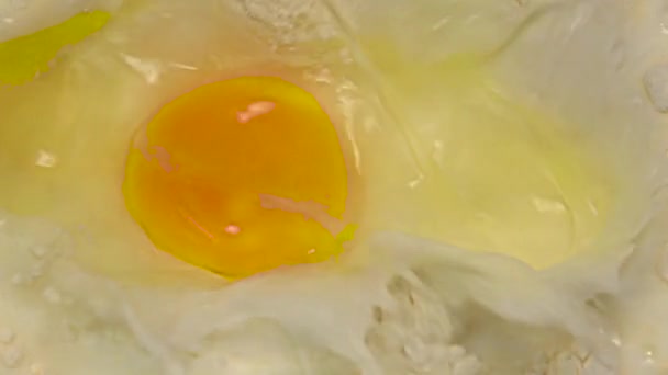 Αυγό πέφτει στο αλεύρι με το γάλα σε αργή κίνηση. Κινηματογράφηση σε πρώτο πλάνο — Αρχείο Βίντεο