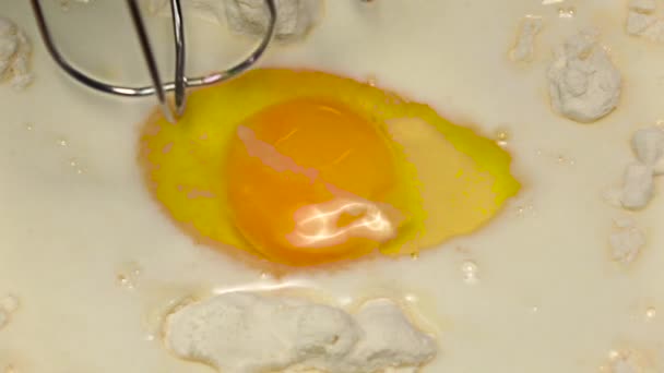 Αναμιγνύοντας το αλεύρι με τα αυγά και γάλα μίξερ, αργή κίνηση. Κινηματογράφηση σε πρώτο πλάνο — Αρχείο Βίντεο