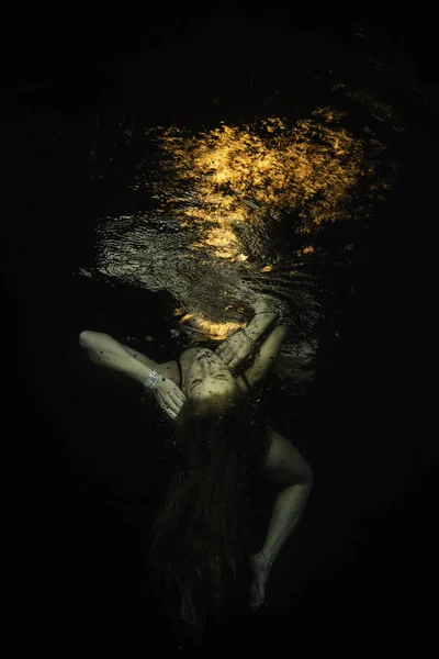 Unconscious girl levitates underwater with fire over the surface — Stock Photo, Image
