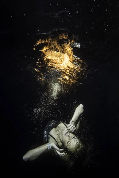 Ragazza incosciente levita sott'acqua con il fuoco sulla superficie — Foto Stock