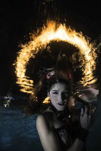 Woman underwater posing with a ring of fire in the background — Stock Photo, Image