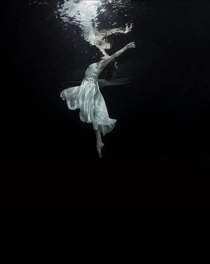 A young ballerina is dancing underwater