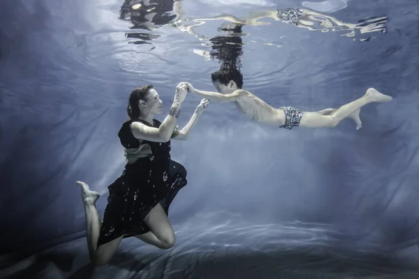 Pregnant woman posing with olderson posing underwater — Stock Photo, Image