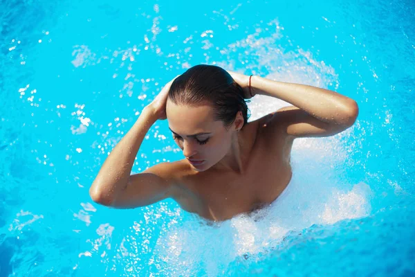 Hermosa mujer en una piscina bajo la estrea del agua — Foto de Stock