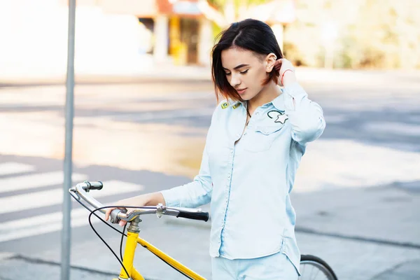 Mulher encantadora com uma bicicleta na estrada — Fotografia de Stock