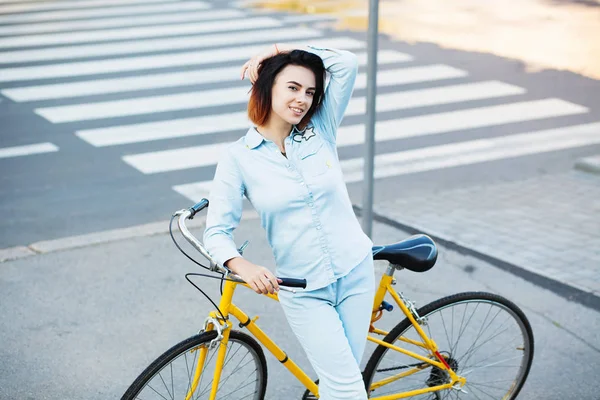 Mulher encantadora com uma bicicleta na estrada — Fotografia de Stock