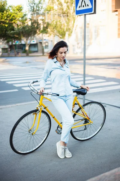 Милая женщина с велосипедом на дороге — стоковое фото