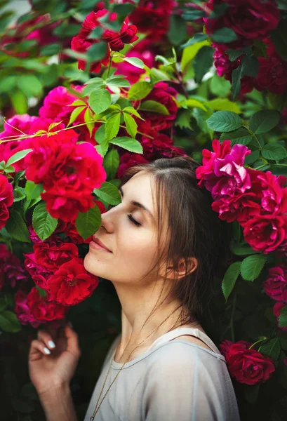 Όμορφη τρυφερή γυναίκα στον κήπο με τριανταφυλλιές — Φωτογραφία Αρχείου
