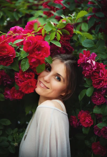 Όμορφη τρυφερή γυναίκα στον κήπο με τριανταφυλλιές — Φωτογραφία Αρχείου