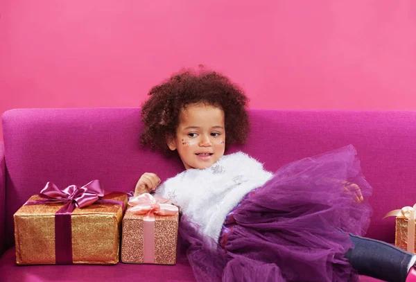 Niña feliz con un montón de cajas de regalo sentado en el sofá —  Fotos de Stock