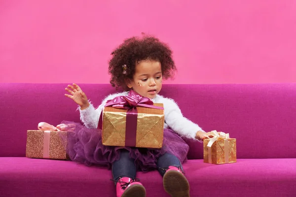 Nettes kleines Mädchen mit vielen Geschenkboxen auf dem Sofa — Stockfoto