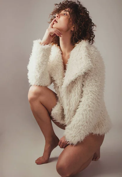 Beautiful woman in furry coat against gray background — ストック写真