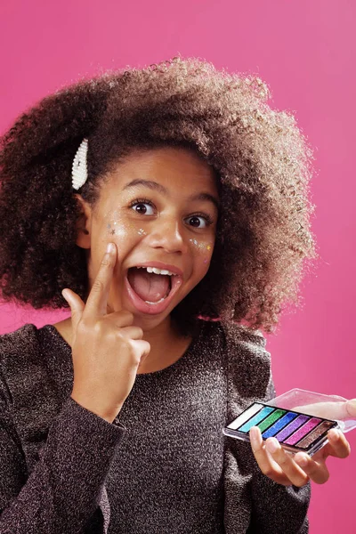 Lovely teenage girl applying festive makeup with glitter — Stock Photo, Image