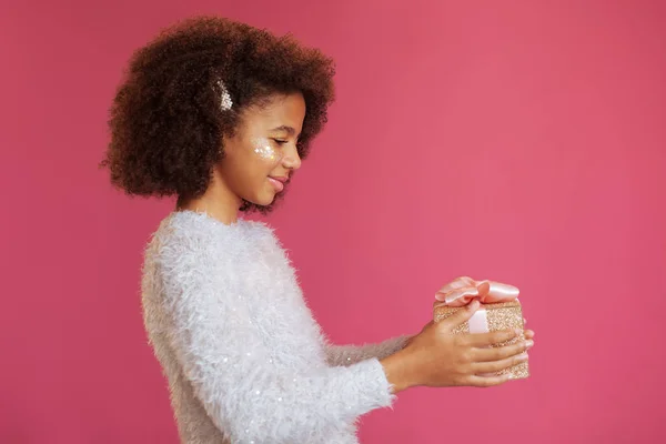 Cute festive girl holding a shiny gift box — Stock Photo, Image