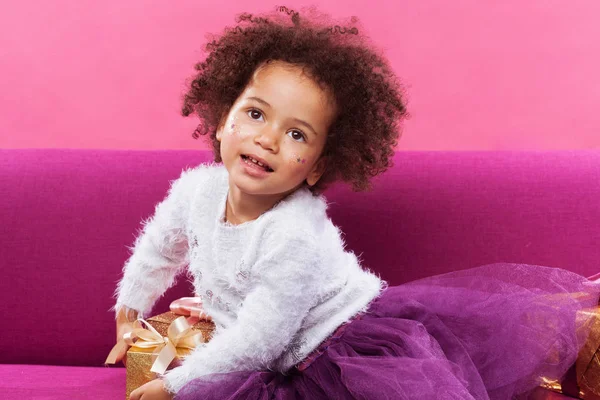 Cute little girl with a lot of gift boxes sitting on sofa — Stock Photo, Image