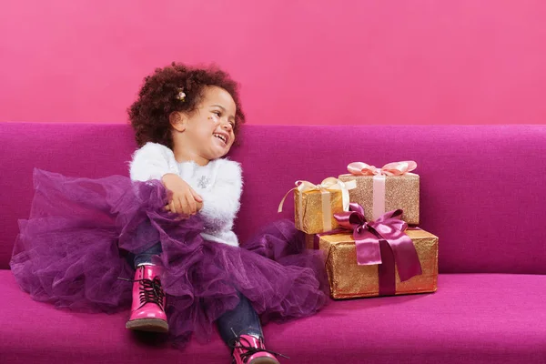 Linda niña con un montón de cajas de regalo sentado en el sofá — Foto de Stock