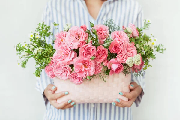 Güzel çiçeklerle dolu sepeti tutan bir kadın.