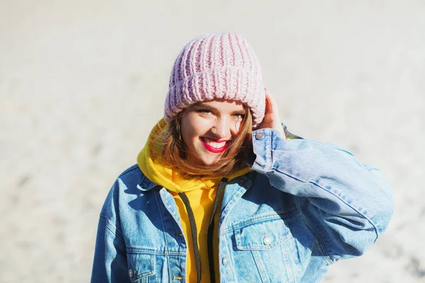 Junge schöne Frau in Jeans und Strickmütze am Strand — Stockfoto