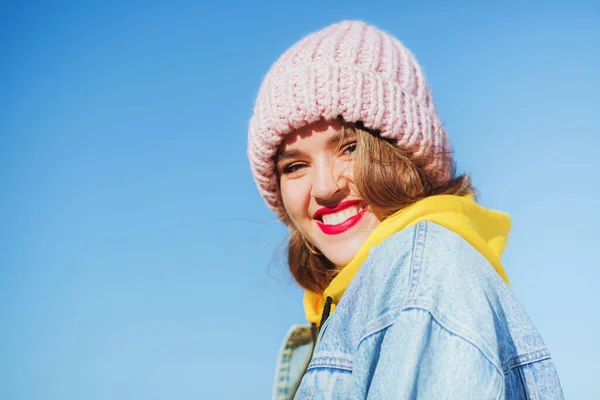 Junge schöne Frau in Jeansjacke und Strickmütze gegen den Himmel — Stockfoto