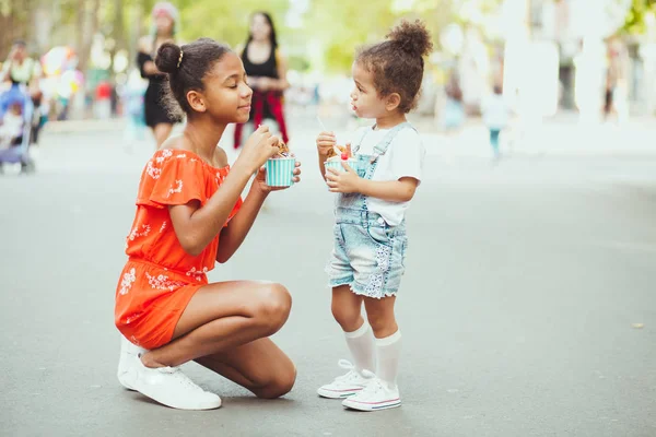 Two cute little sisters eating ice-cream in the street — 스톡 사진
