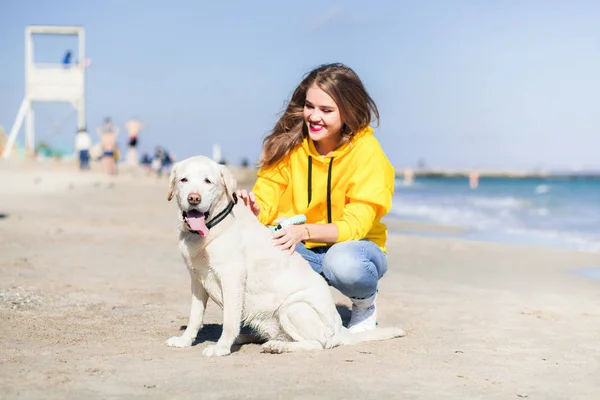 Schöne junge Frau, die mit dem Hund am Strand spazieren geht — Stockfoto