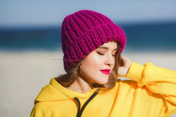 Mujer hermosa joven en sudadera amarilla y sombrero de punto púrpura brillante — Foto de Stock