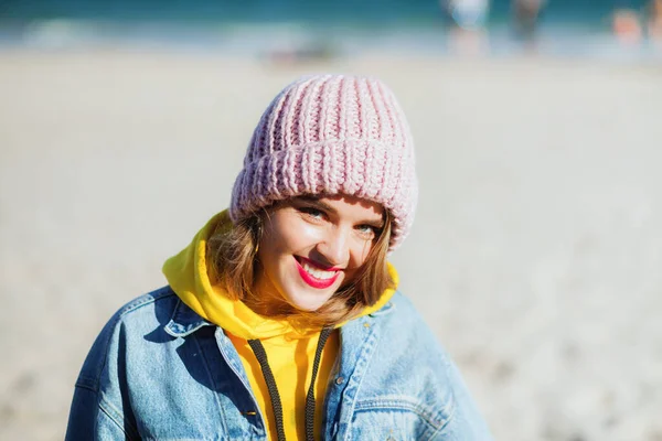 Joven hermosa mujer en chaqueta de mezclilla y sombrero de punto en la playa — Foto de Stock