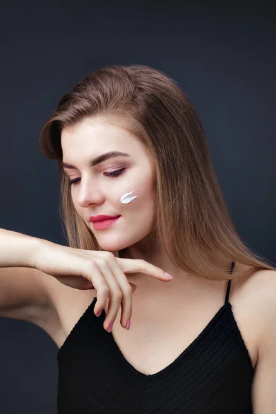 Mujer encantadora con una piel suave y saludable aplicando crema en su cara — Foto de Stock